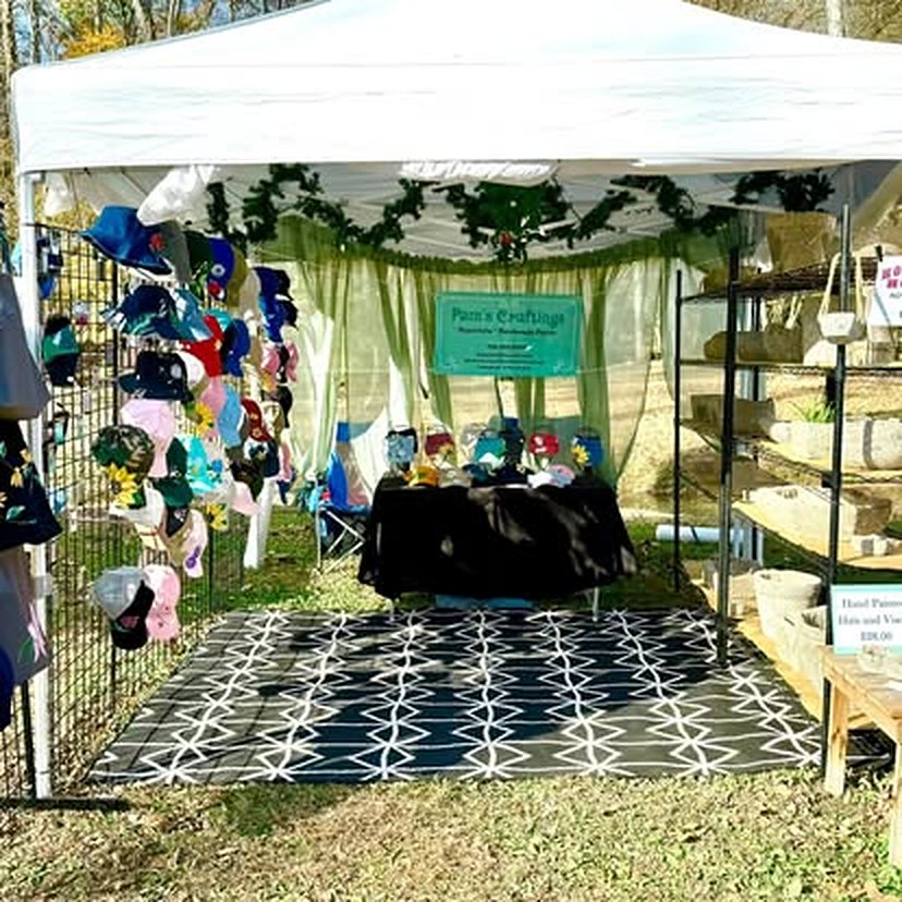 Pam's Craftings booth with a wall of caps